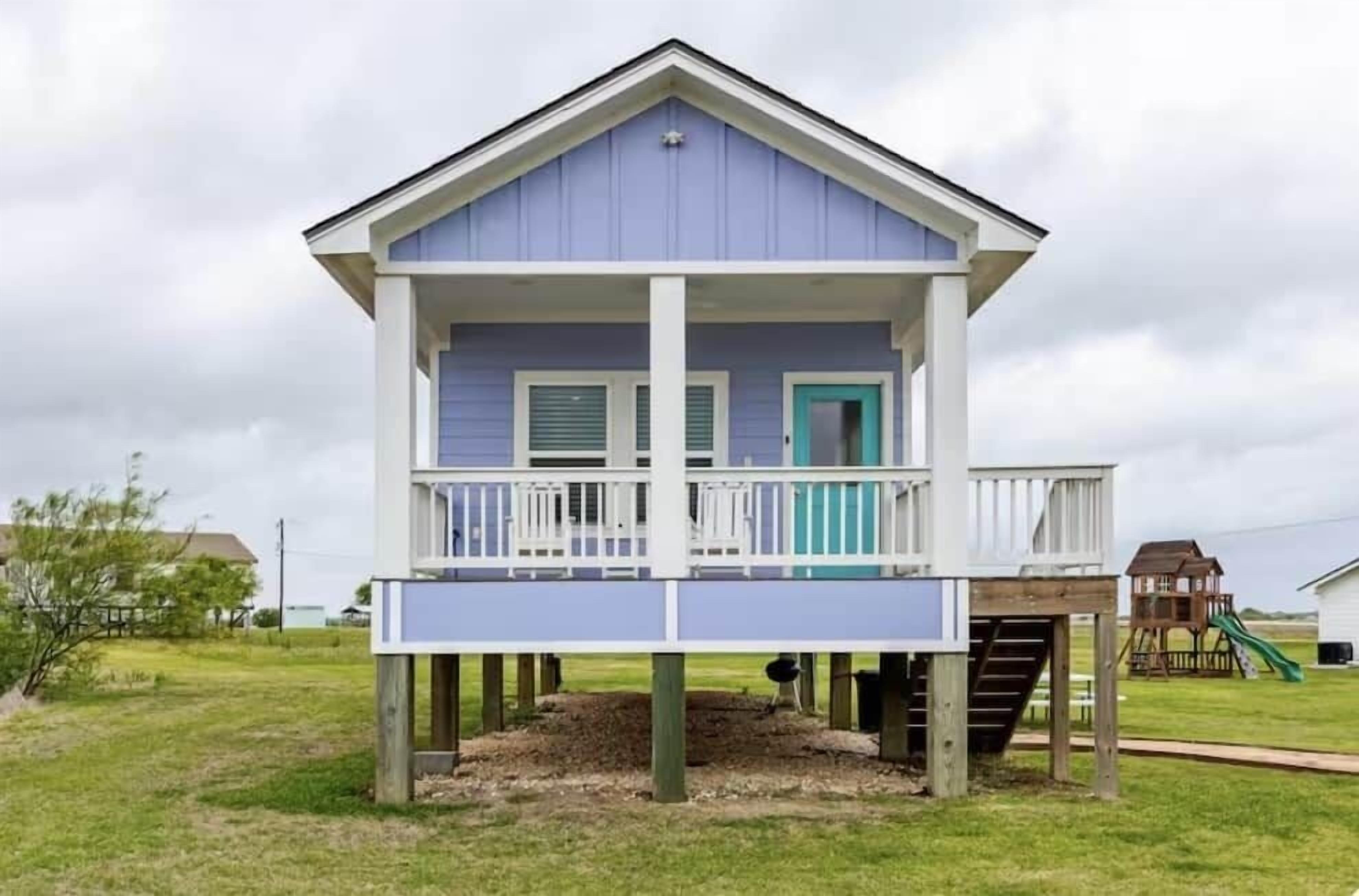 A two-story house with a balcony, a front door, and a small deck area.