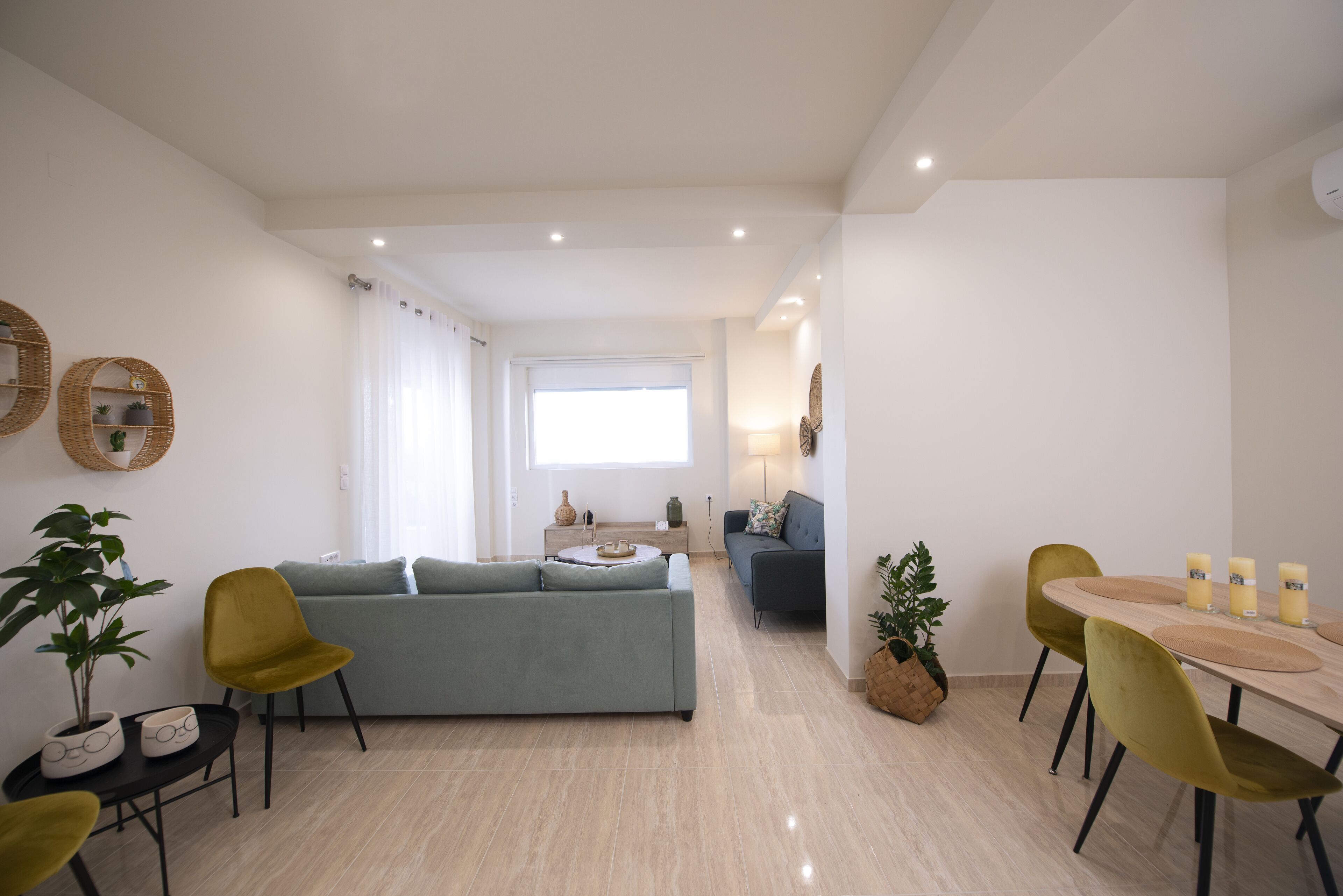 Un saló modern amb un sofà, seients, una taula de menjador i una cuina al fons.