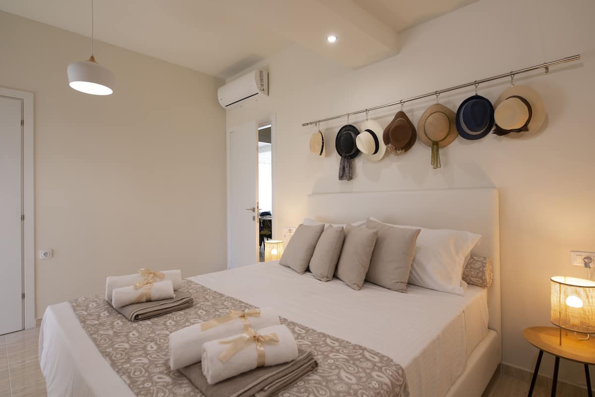 A neatly made bed with towels, a headboard with hats, and a bedside lamp.