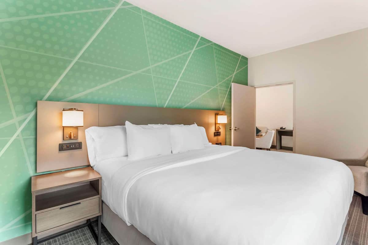 A hotel room with a large bed, two bedside tables with lamps, a desk, and a chair.