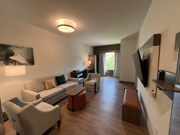 A modern living room with a sofa, armchairs, a coffee table, and a TV mounted on the wall. - Comfort Suites Gatlinburg Downtown-Convention Center (Gatlinburg)