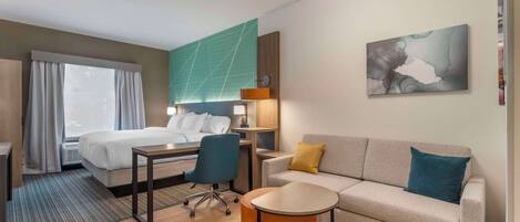 Una habitación de hotel con una cama, un escritorio, una silla, un sofá y una pequeña mesa.