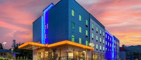 A modern hotel with a flat roof, multiple windows, and a well-lit entrance area.
