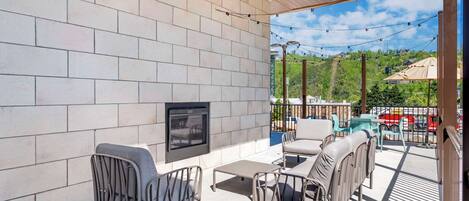 A covered outdoor area with a fireplace, seating, and a view of the surrounding landscape.