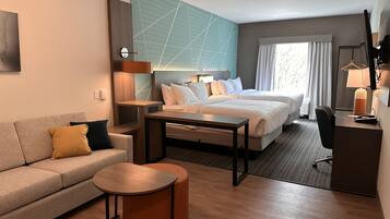 Une chambre d’hôtel avec un lit double, un canapé, une petite table et un bureau.