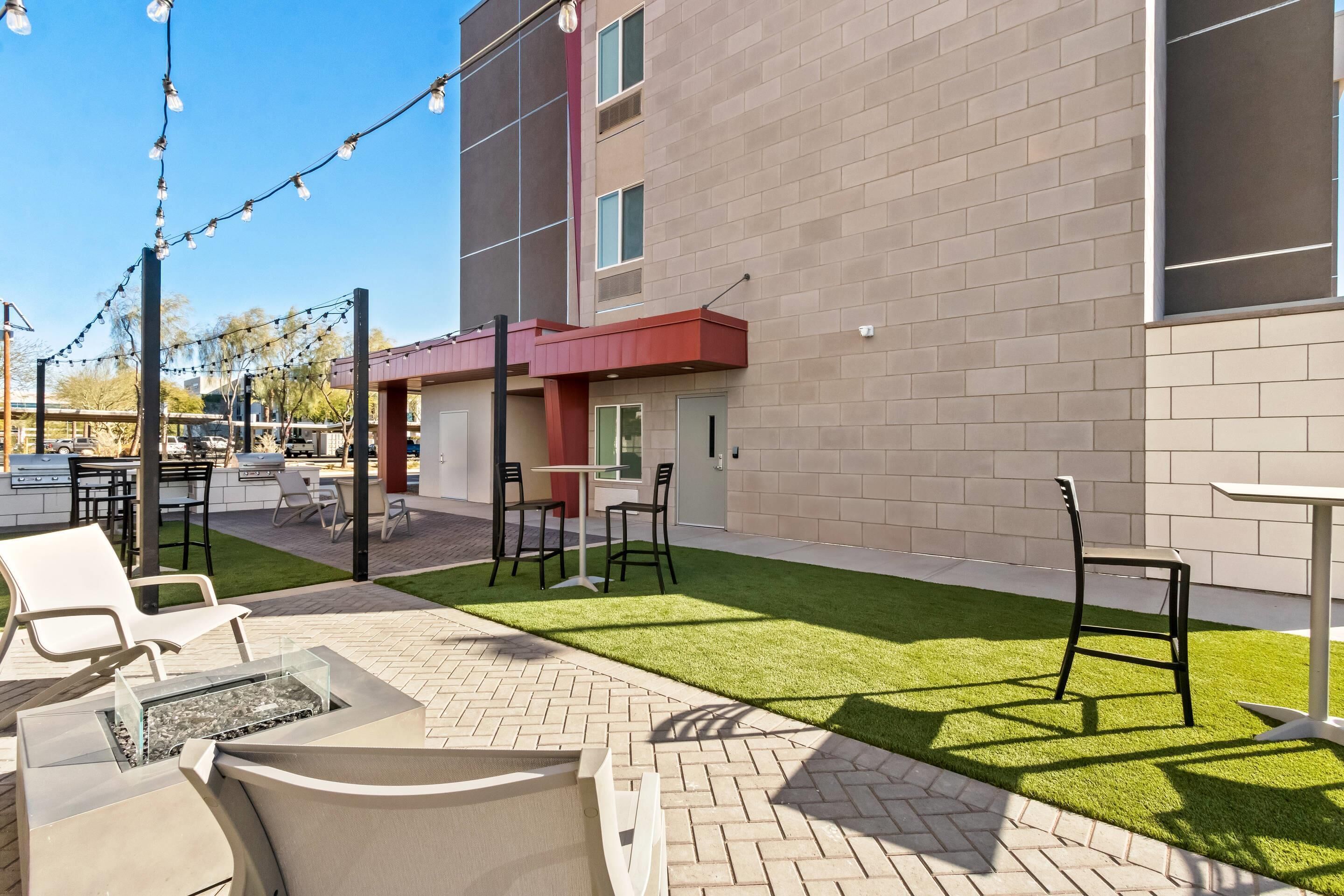 An outdoor patio with seating, a fire pit, and string lights.