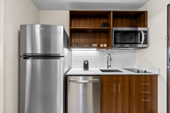 Une cuisine moderne équipée d’un réfrigérateur en acier inoxydable, d’un four à micro-ondes, d’un lave-vaisselle et de meubles de rangement en bois.