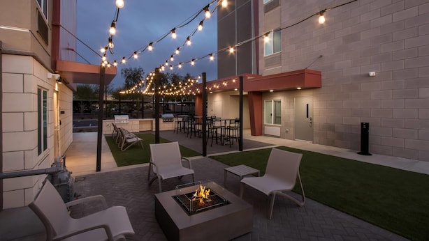 Un patio al aire libre con un hogar para fuego, asientos e iluminación colgante.