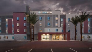 Un hotel moderno con un llamativo letrero de 'Everhome Suites', una entrada bien iluminada y un estacionamiento.