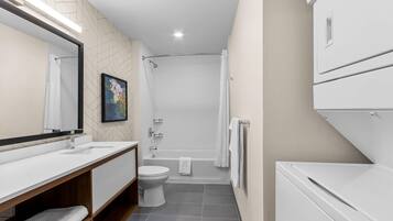 Un baño moderno con ducha, inodoro y un espejo grande.
