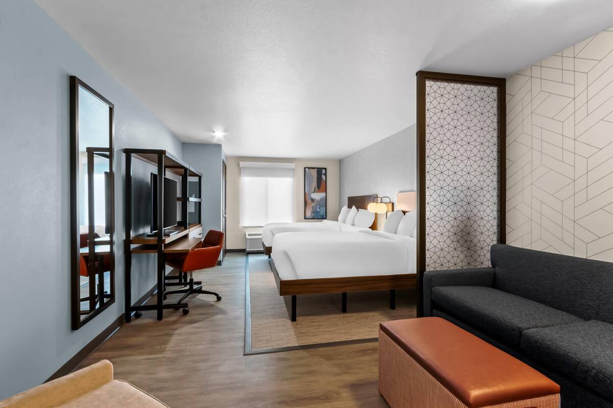 Una habitación de hotel con una cama grande, un escritorio con computadora, un sofá y una mesita.