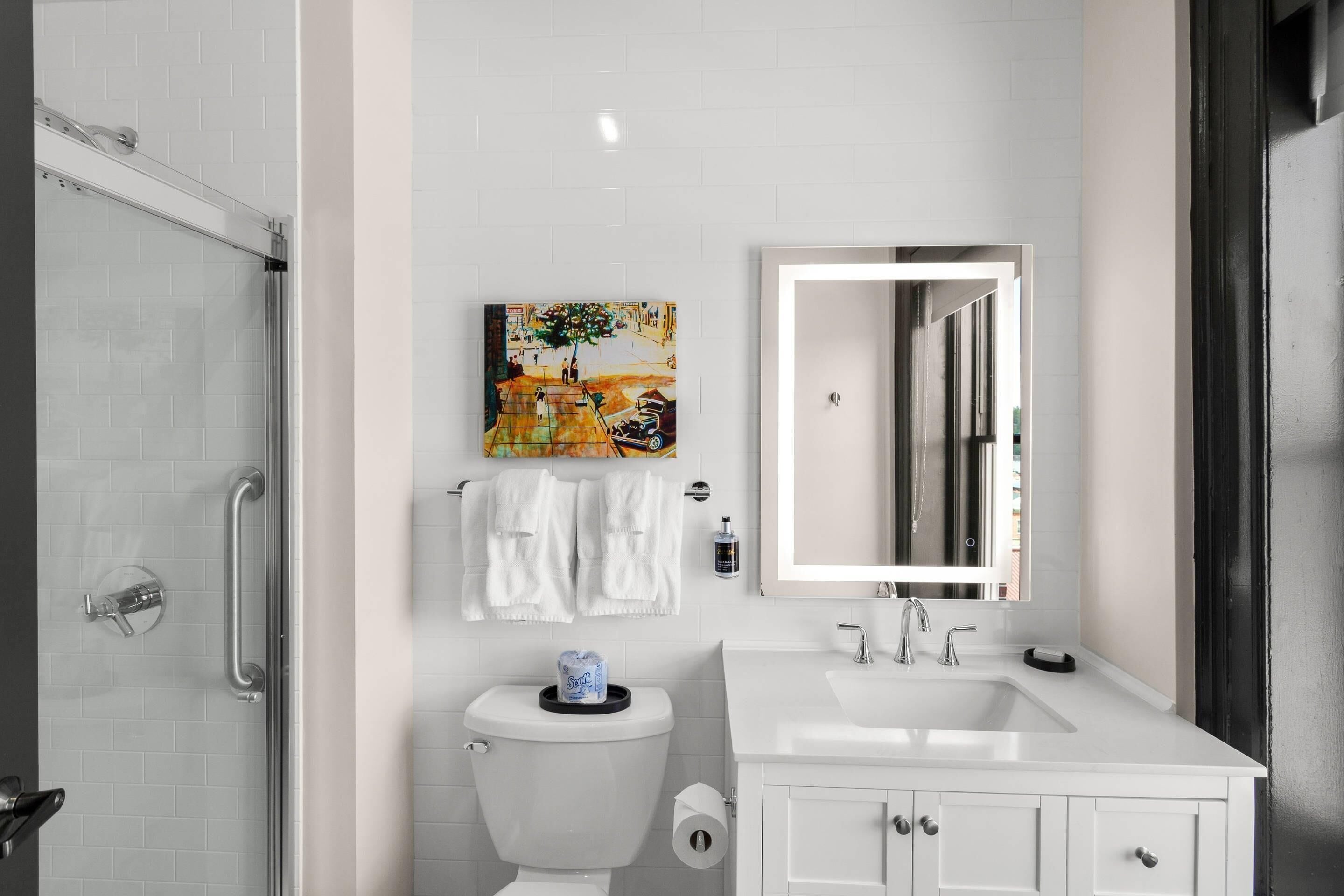 Une salle de bain moderne avec une douche à parois de verre, des toilettes, un lavabo et un miroir.