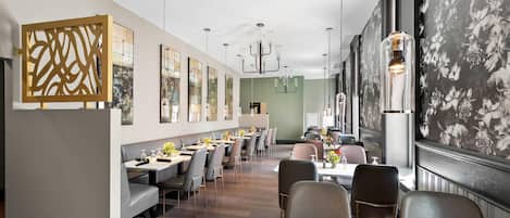Un restaurante moderno con mesas largas, sillas y una araña.