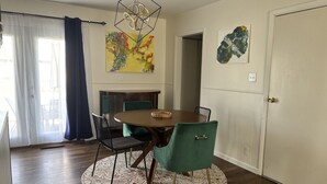 Un comedor con una mesa redonda, sillas color turquesa y una alfombra estampada.
