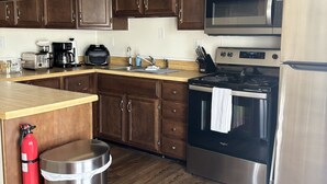 Una cocina con armarios de madera, una estufa de acero inoxidable, un microondas y un refrigerador.