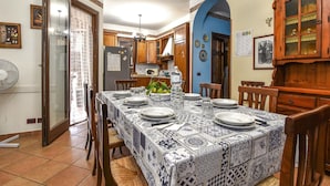 Zona pranzo con tavolo apparecchiato per quattro, circondato da sedie in legno.