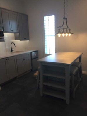 Enjoy cooking in this well-equipped kitchen with a central island, sink, and pendant light.