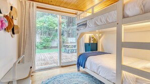 A bunk bed room with a view of a wooden deck and a picnic table. - Four Bears by Avantstay Walk to Beach, Hot Tub, Ocean View (Arch Cape)