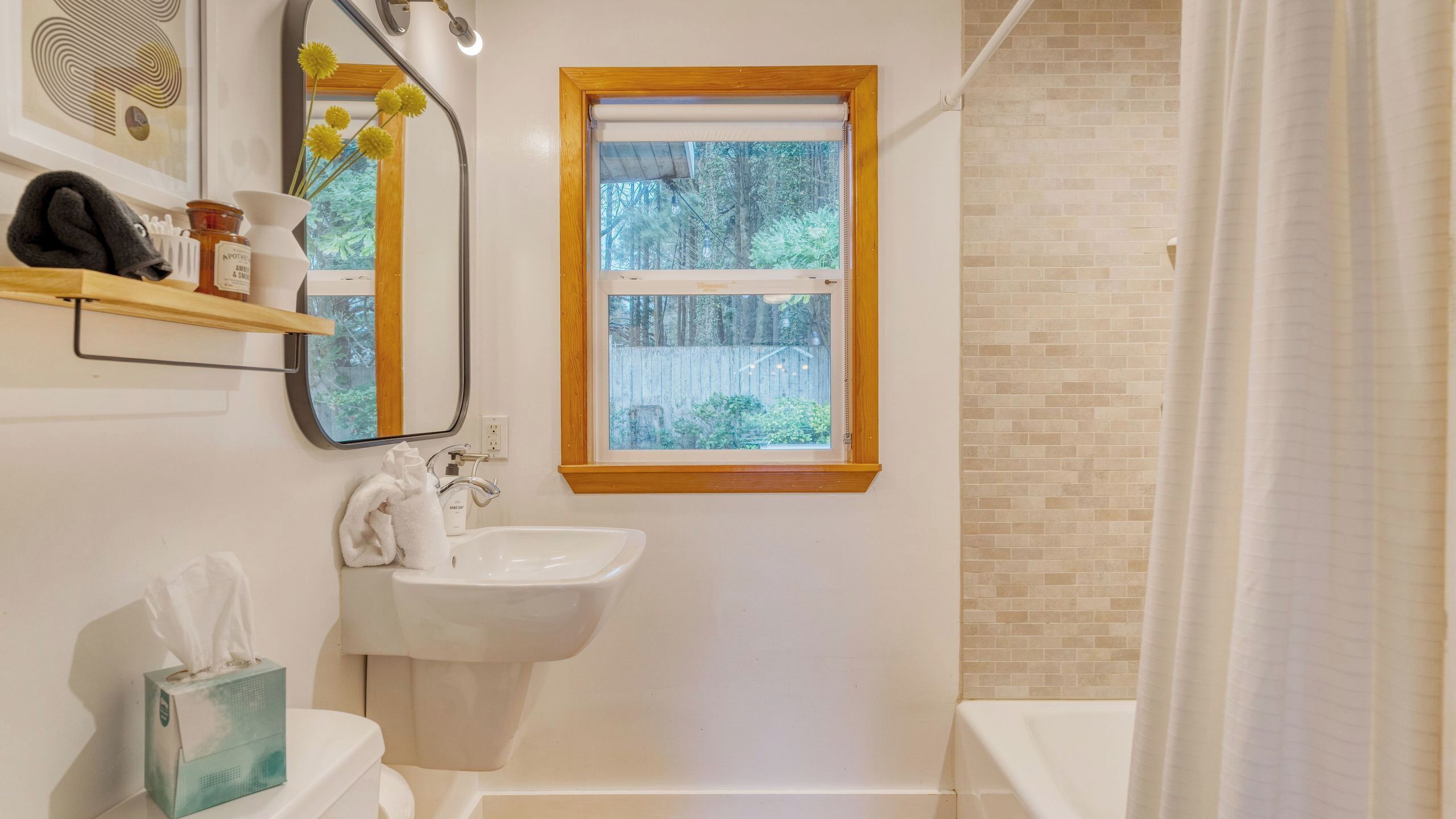 A bathroom with a sink, mirror, and window.