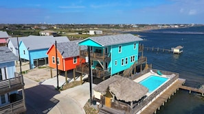 A waterfront property with elevated houses, a swimming pool, and a dock.