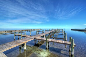 A wooden pier extending into calm water with clear skies above.