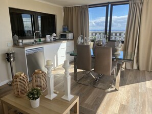 A modern kitchen with a view of the city, a dining area with a glass table, and a cozy seating arrangement. - Luxury Mencey Penthouse (Santa Cruz de Tenerife)