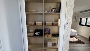 Un vestidor amplio con varias estanterías, un enchufe y diferentes cajas de almacenamiento.