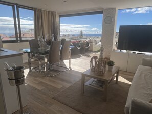 A modern living room with a dining area, large windows with a city view, and a flat-screen TV. - Luxury Mencey Penthouse (Santa Cruz de Tenerife)