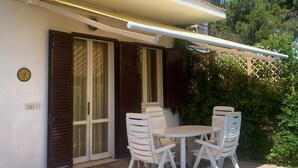 Eine Terrasse mit Tisch und Stühlen, ein überdachter Bereich und ein Balkon mit Geländer.