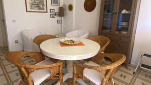 Ein Essbereich mit Korbstühlen, einem runden Tisch und einem Schrank mit Glastüren.