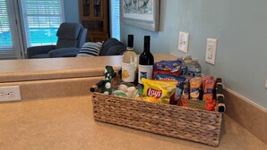 En køkkenbordplade med en flettet kurv med snacks, en vinflaske og en pose chips.