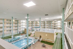 Ein Poolbereich im Innenbereich mit mehreren Ebenen, Balkonen und Liegestühlen.