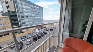 Un balcón con vista a un estacionamiento y un edificio de varios pisos y balcones.