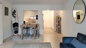 Una sala de estar moderna con comedor, un sofá azul y una decoración con una tabla de surf.