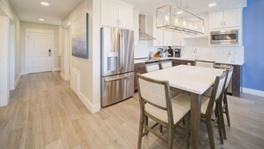 A modern kitchen with stainless steel appliances, a central island, and a dining area with chairs. - Pool View, Great Amenities | Luxe 6-Guest Haven (Destin)