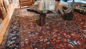 Una sala de estar moderna con una mesa de centro de vidrio, alfombra estampada y mobiliario de cuero.