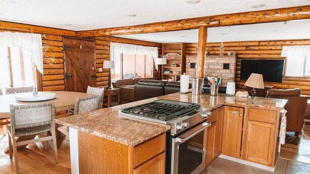 Interior de una cabaña de troncos con cocina, comedor y sala de estar.