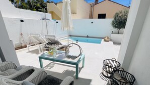Un espace patio aménagé avec des meubles en osier, une table en verre et une piscine.