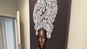 Un couloir avec une grande œuvre d’art accrochée au mur, une porte et deux paniers posés sur le sol.