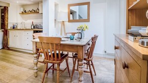 Une cuisine moderne avec des meubles en bois, une table à manger et des chaises. Un miroir est accroché au mur et un radiateur se trouve au-dessus de l’évier.