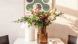 A dining table with a vase of flowers, two cups, and an open book. - TurnKey | Charles Square Studio II (Praha 2)