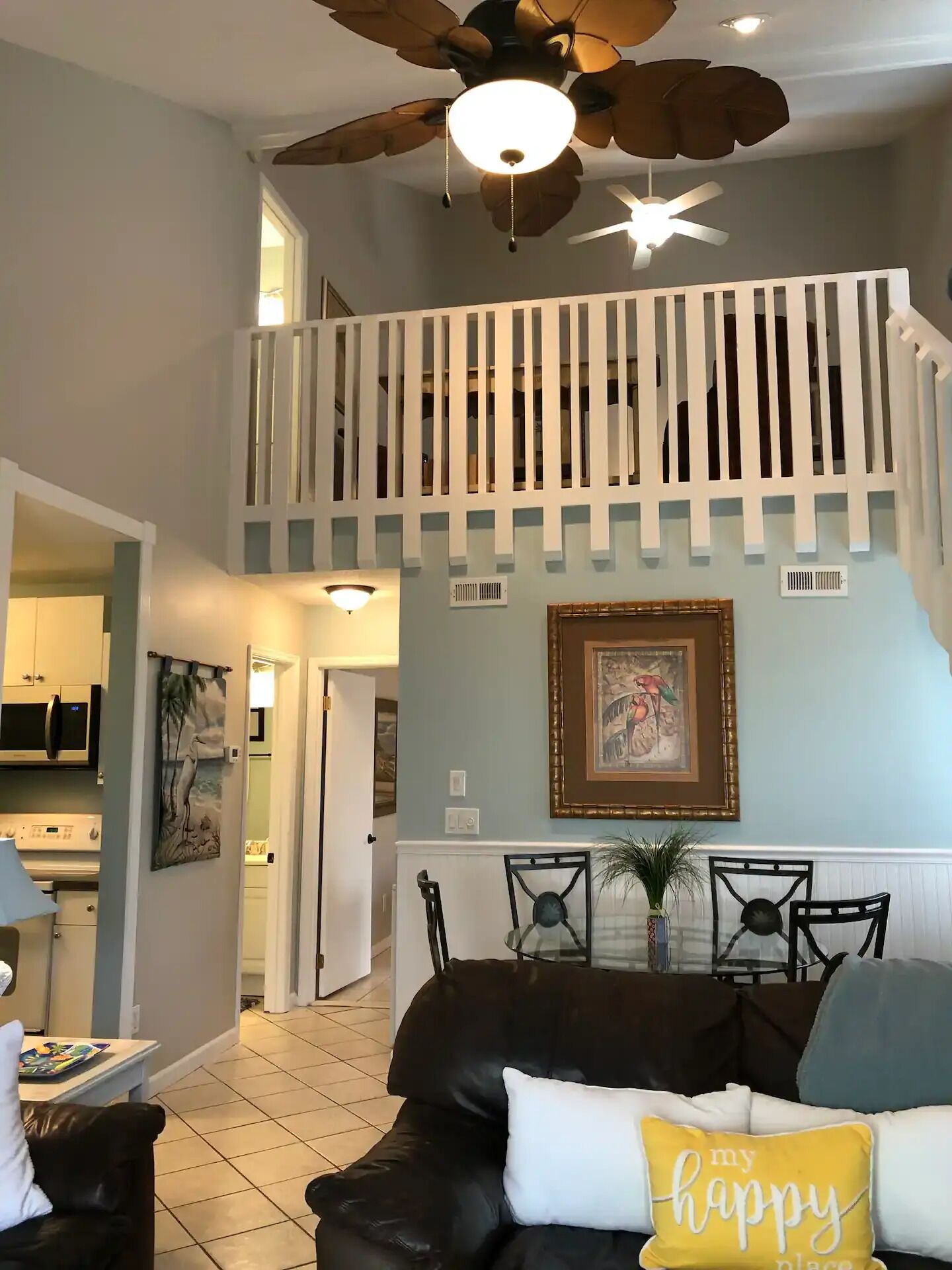 A spacious living room with a high ceiling, a ceiling fan, and a staircase leading to an upper level.