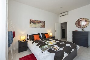 Ein Schlafzimmer mit Bett, Nachttischen, einem roten Teppich, einem Spiegel und einem Bild an der Wand.