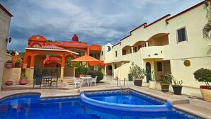A hotel courtyard with a swimming pool, outdoor seating, and potted plants. - Hotel Oasis (Comondu)