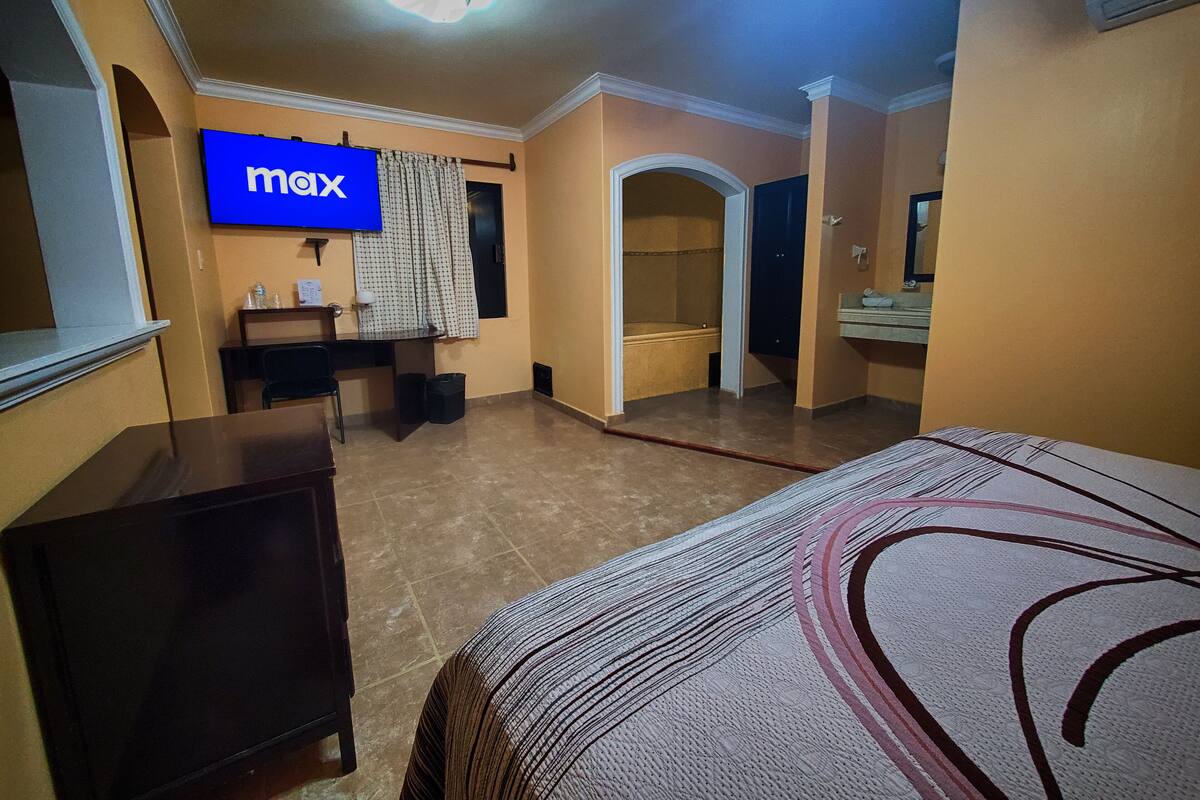 Hotelkamer met een bed, een bureau, een stoel, een televisie en een badkamer.