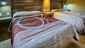 A hotel room with two beds, a ceiling fan, a wall-mounted air conditioner, and a bedside table with a lamp. - Hotel Oasis (Comondu)