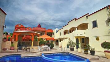 A hotel courtyard with a swimming pool, outdoor seating, and potted plants.