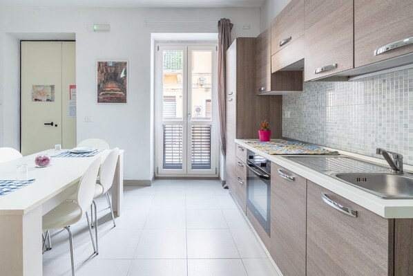 Een koelkast, een oven, een kookplaat, kookgerei, borden en bestek