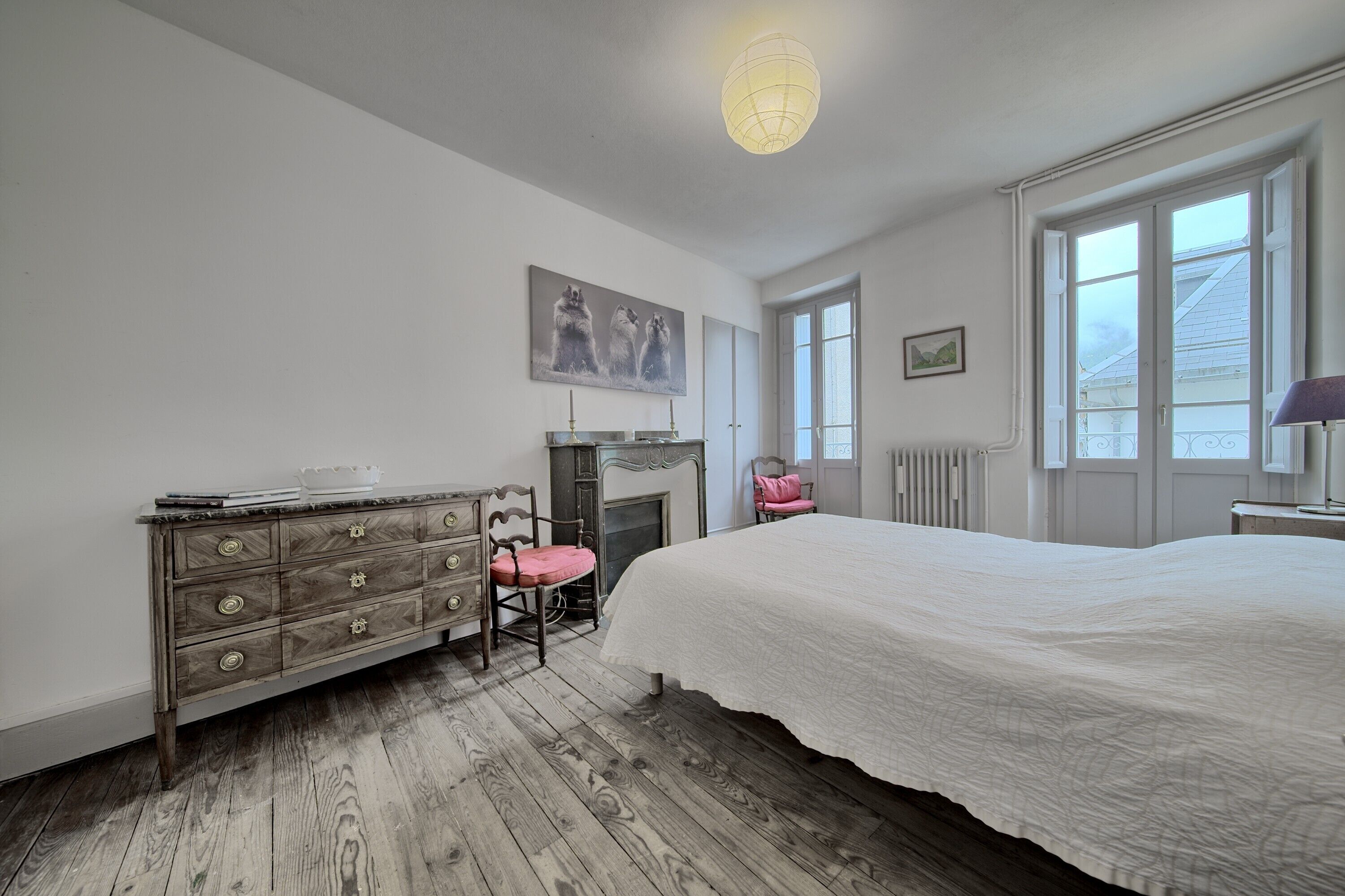 Ein Schlafzimmer mit einem großen Bett, einem Schminktisch, einem Sessel, einem Kamin und einem Fenster.