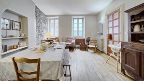 Un comedor amplio con una mesa alta, bancos y vistas al jardín a través de amplios ventanales.